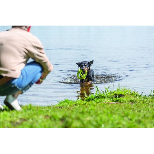 Hond apporteert Trixie Aqua Toy Grijper limoengroen in meer, baasje wacht op de oever