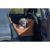 Hond zittend in de cognackleurige hondenautostoel op de achterbank van de auto