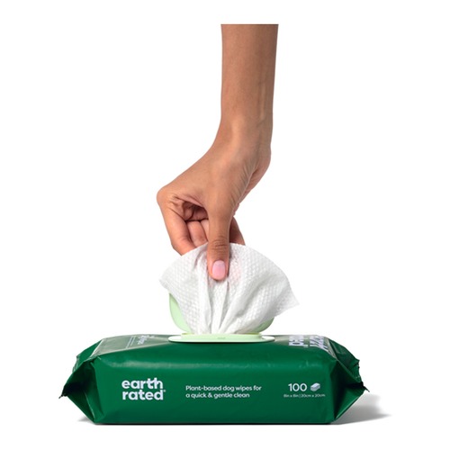 Hand houdt een vochtig Earth Rated hondendoekje vast boven de verpakking