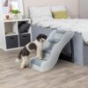 Hond stapt op de onderste trede van een trap tegen het bed